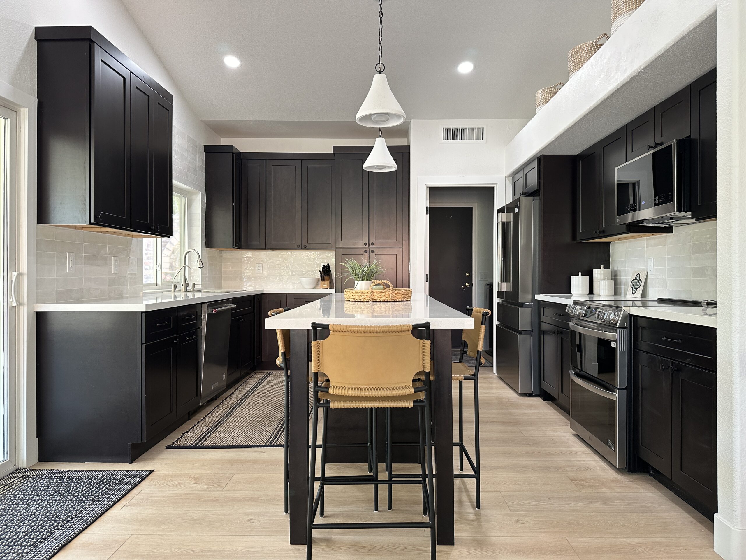 Remodeled kitchen with dark cabinets and a waterfall island by T26 Design Build