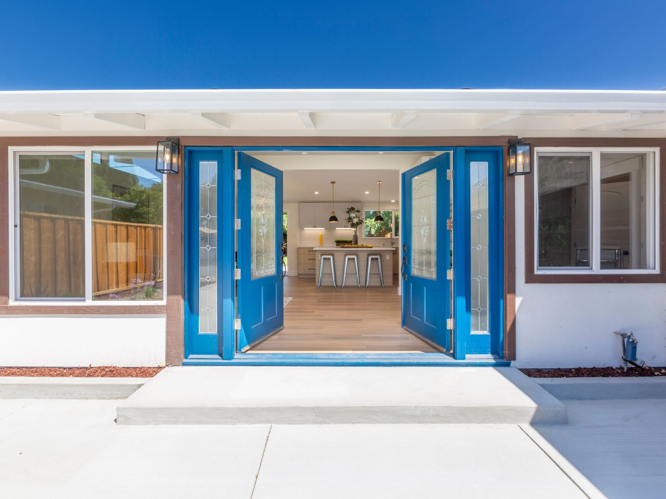 Front view of a house with open blue doors with modern kitchen interior visible behind
